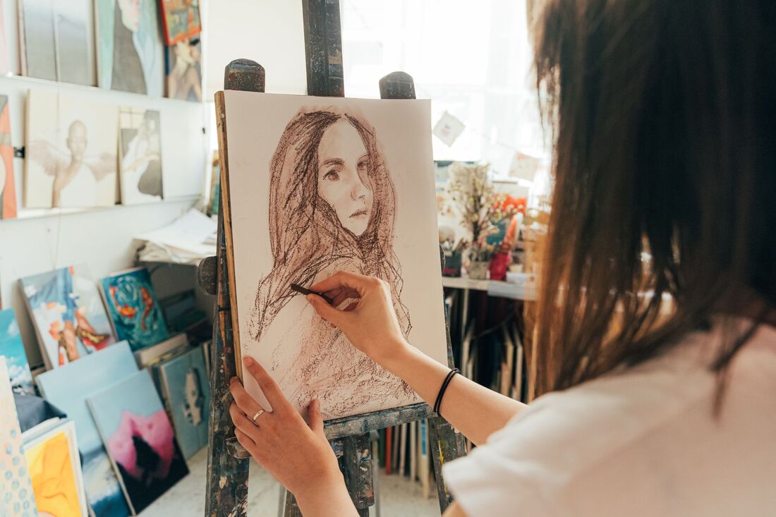 An artist drawing a portrait on canvas in a home studio
